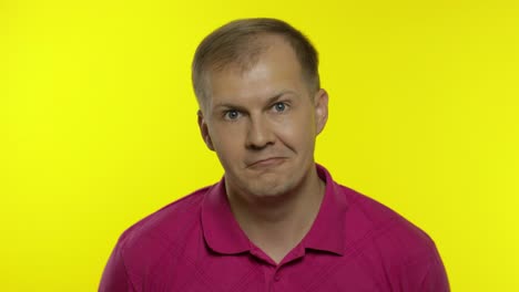 portrait of young caucasian man posing in pink t-shirt. confused handsome guy shocked, surprised