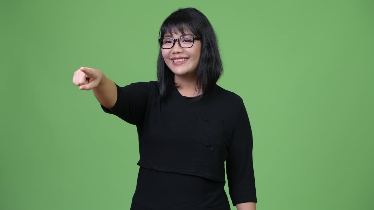 Smuk glad asiatisk forretningskvinde, der smiler og peger