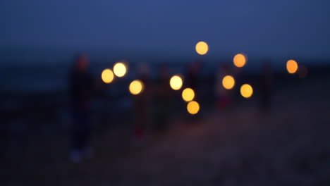 people holding sparklers on a dark beach at night
