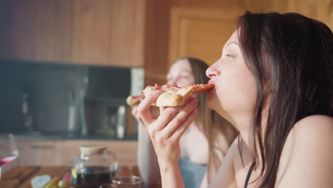two students having a good time as they enjoy a slice of pizza, sharing a relaxed moment in the kitchen, laughing and savoring their meal with joy