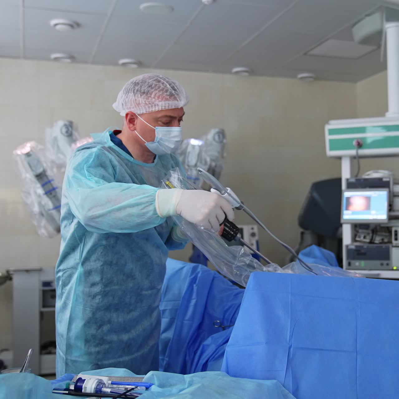 Two surgeons in a modern operating theatre with working screen on. Monitor showing the inner organ. Doctor changing instrument