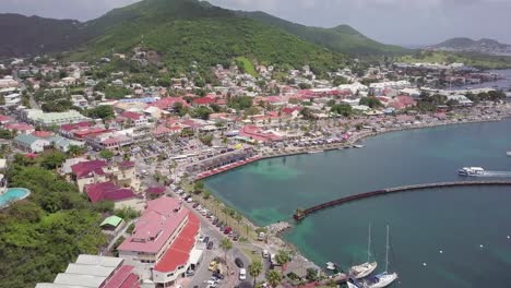 aerial footage of saint martin leeward islands in the caribbean sea, drone reveal small town village with harbour and mountain sea view