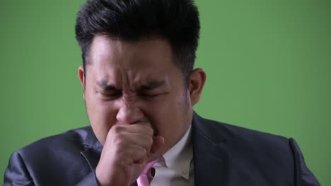 young handsome overweight asian businessman against green background