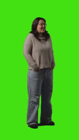 Vertical-Video-Full-Length-Portrait-Shot-Of-Smiling-Casually-Dressed-Young-Woman-Standing-Against-Green-Screen-1