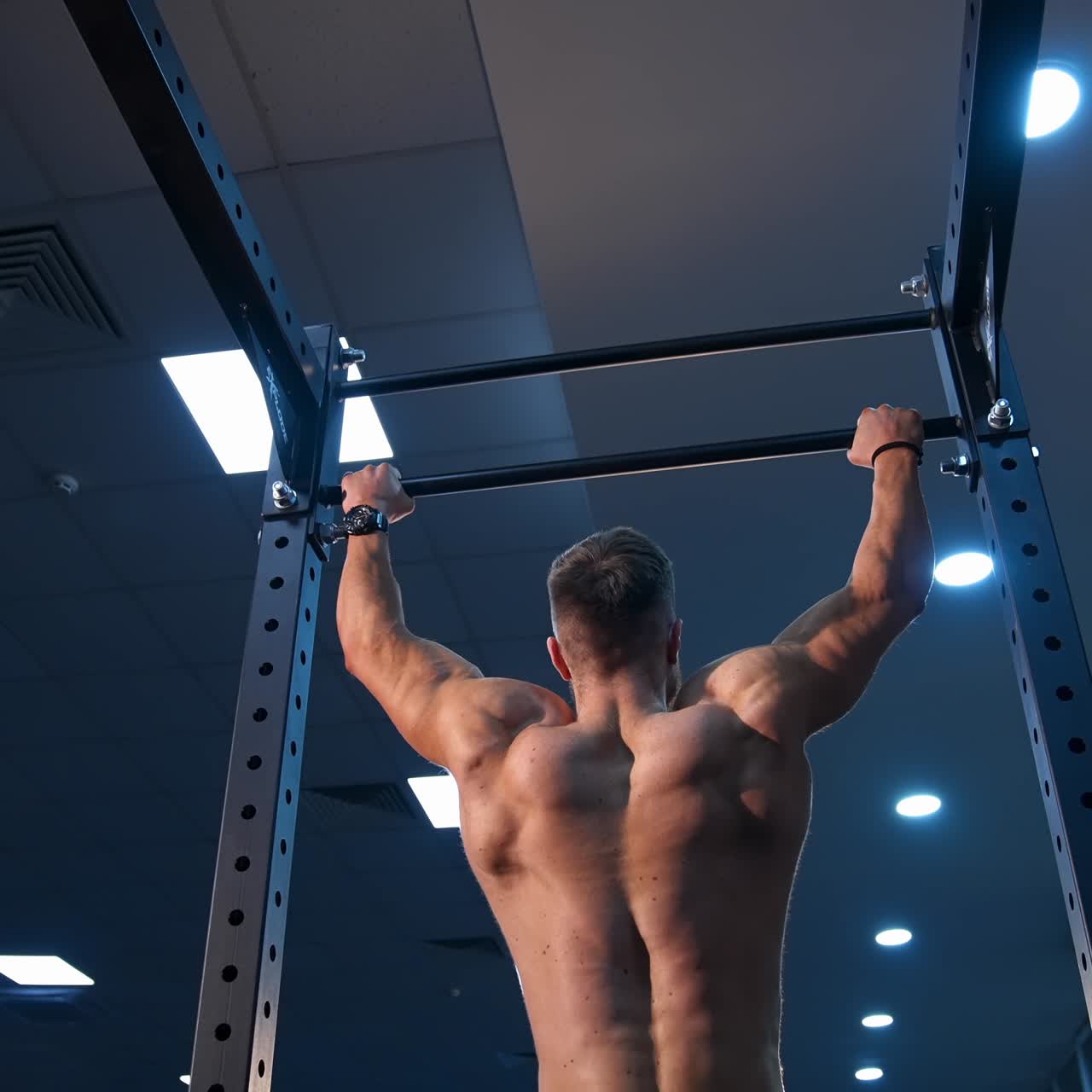 Handsome man gumped on horisontal bar. Male sportsman trains in gym. Slow motion