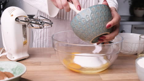 Woman-Combine-White-Sugar-In-Eggs-On-A-Glass-Bowl---Making-A-Delicious-Carrot-Cake