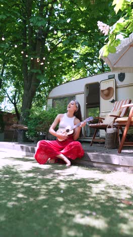 woman playing ukulele in a camper van garden