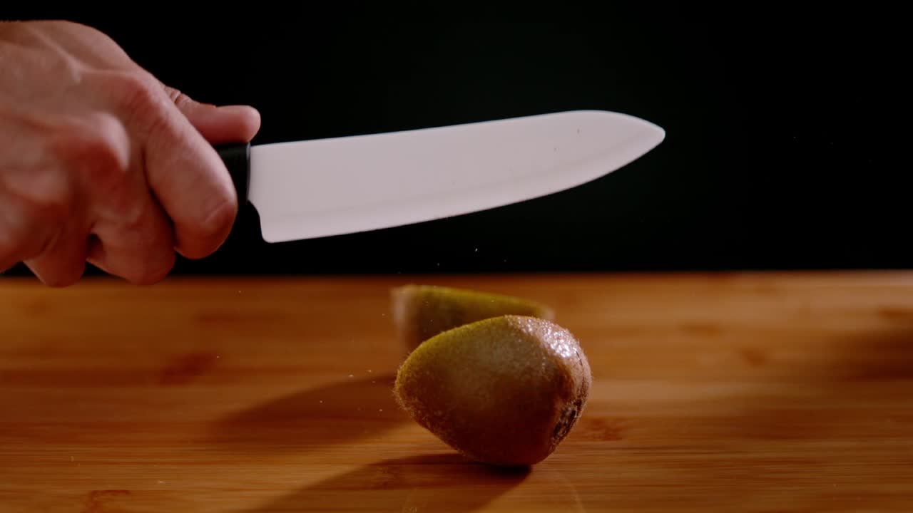 cuchillo de chef afilado corta kiwi por la mitad con potencia, vista en cámara súper lenta