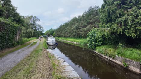 scenic canal with a moored boat and walkers on the towpath