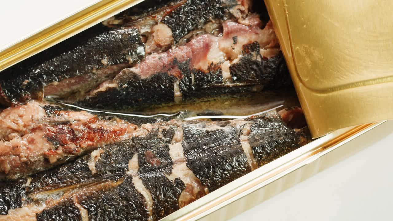 Opening sardine fish or tuna can, man open the canned anchovy on the table. Close up on professional kitchen.