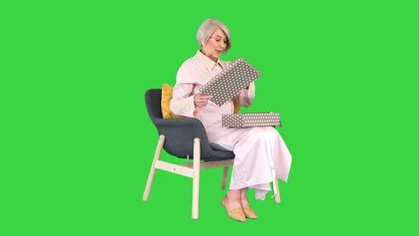 happy smiling senior woman opening a gift box on a green screen, chroma key