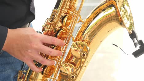 manos de hombres tocando el saxofón al aire libre