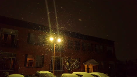 una ligera nevada bajo una cálida lámpara de calle en el centro de st. catharines, una tranquila noche de invierno