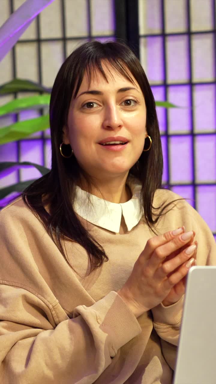 Donna sorridente che parla e gesticola in uno studio moderno