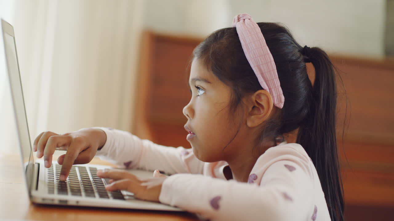 niña aprendiendo a escribir en una computadora portátil en casa