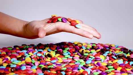 hand playing with colorful candies on surface