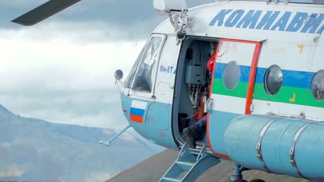 person boarding a helicopter in mountainous terrain