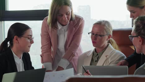 a group of girls in business suits gather around a table and communicate with each other during a business meeting to solve problem and resolve issue