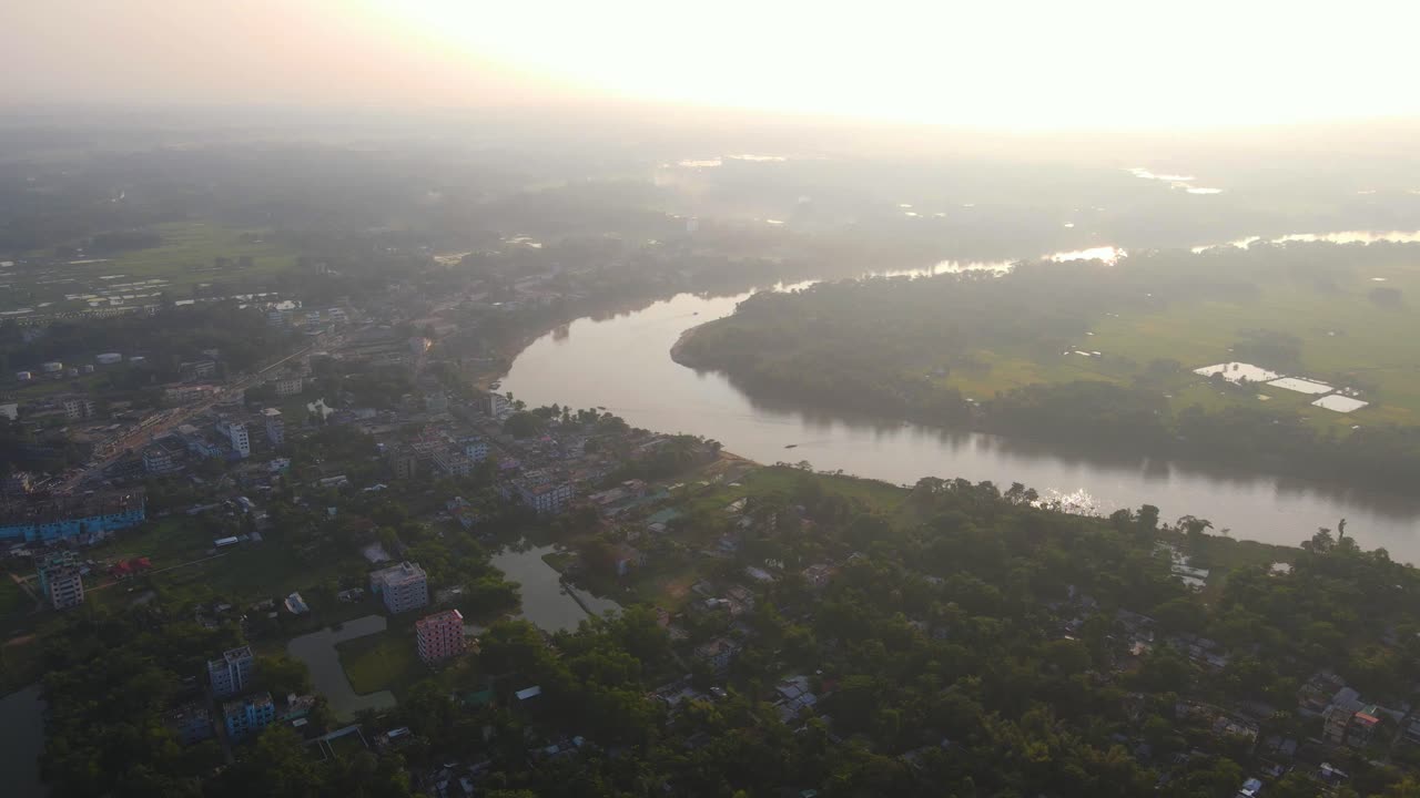 impresionantes imágenes aéreas de una tranquila ciudad suburbana en asia, enclavada junto a un río sinuoso, bañada por el cálido resplandor de un impresionante amanecer en una mañana temprana