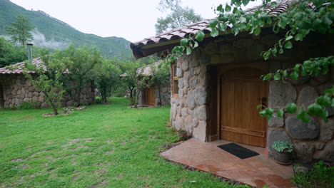 exterior of stone small houses huts in countryside with green grassy yard, sacred valley peru