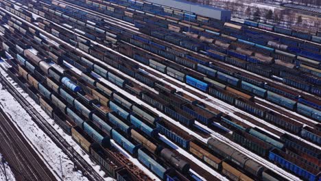 vastas filas de material rodante esperan en el patio de trenes cerca de katowice polonia - toma de seguimiento de drones aéreos de izquierda a derecha - paisaje industrial de invierno cubierto de nieve