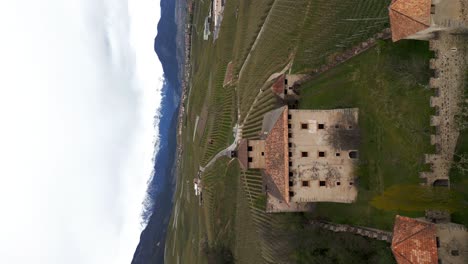 Vertical-aerial-view-of-scenic-Castel-Nanno,-a-castle-in-the-middle-of-the-idyllic-Italian-village-of-Val-di-Non