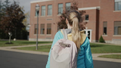 a child with a briefcase walks to a school building in the united states