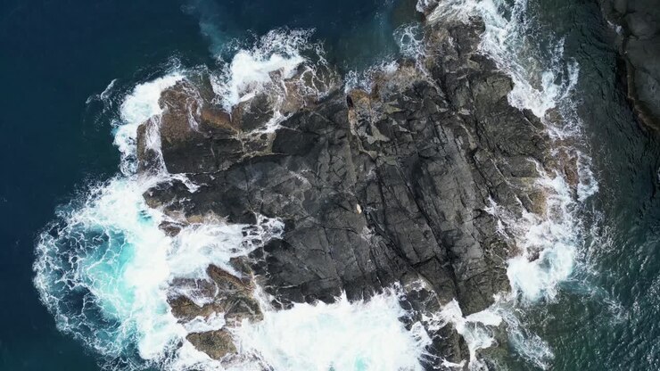 Inquadratura aerea cinematografica dall'alto di forti onde oceaniche che si infrangono su rocce costiere frastagliate a Catanduanes, Bicol.
