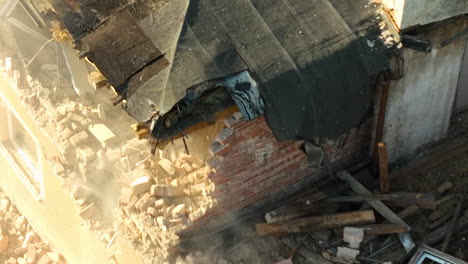 close-up shot of an excavator claw breaking through a roof structure during a demolition process, with dust and debris