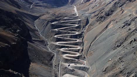 Dolly-Out-Luftaufnahme-Der-Straße-Cuesta-Caracoles,-Grenze-Zwischen-Chile-Und-Argentinien,-Lastkraftwagen,-Die-Durch-Die-Kurven-Fahren,-Sonniger-Tag