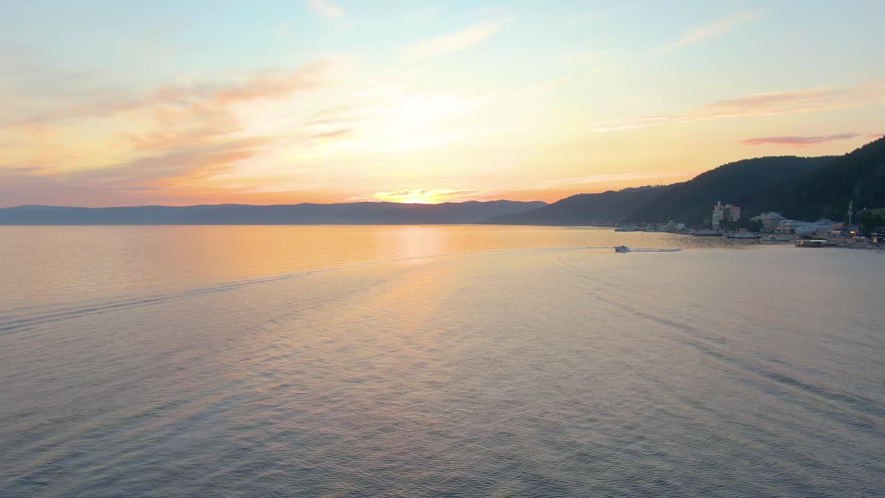 산과 작은 마을이 있는 호수 위의 일몰