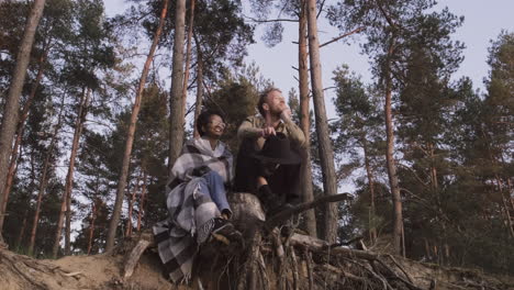 una mujer joven y un chico contemplando la puesta de sol en el bosque