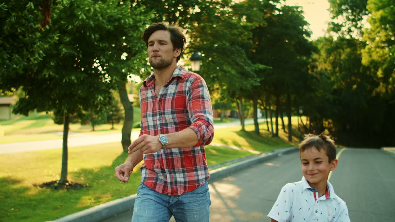 hombre y niño positivos caminando por la calle. padre y hijo felices bailando al aire libre