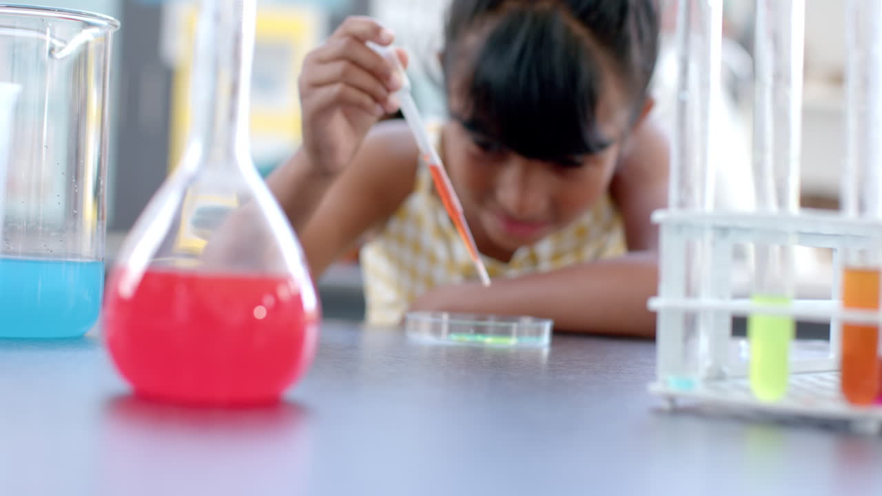 In a school classroom, a young biracial student examines a chemical reaction