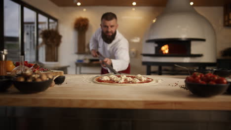 chef cook preparing pizza in kitchen. man taking food in restaurant stone oven.