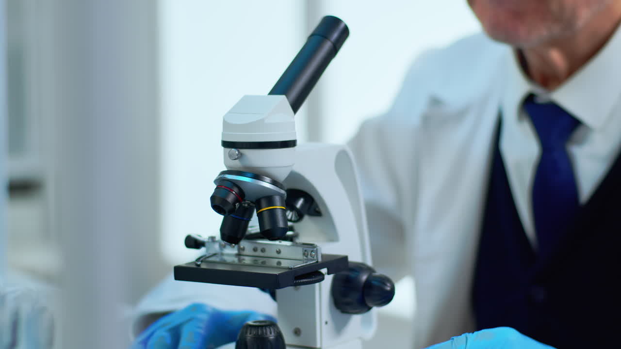 Elderly man in lab making research using microscope