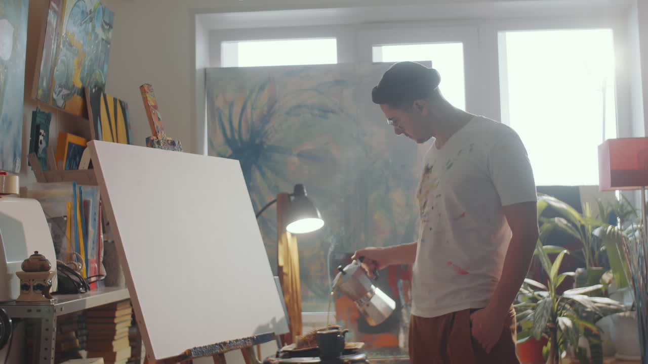 Kunstner drikker kaffe og tegner billede i atelier
