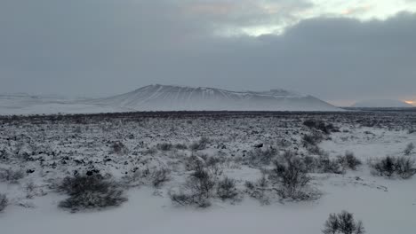 Luftpanoramaaufnahme-Des-Berühmten-Hverfjall-Kraters-Während-Des-Verschneiten-Wintertages-Mit-Dichten-Wolken-Am-Himmel-Während-Des-Sonnenuntergangs-Am-Horizont