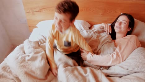 mother and son having fun in bed in the morning