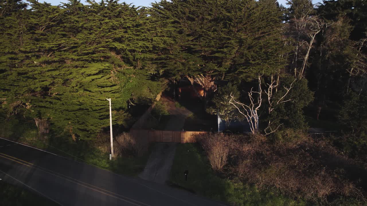 골든 아워에 울창한 나무에 숨겨진 게이트 하우스를 향해 공중으로 하강