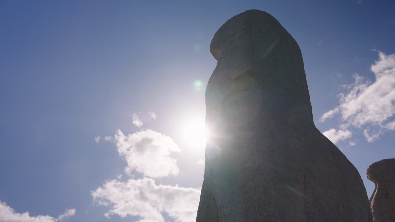 Il sole sorge da dietro una statua Moai, silhouette di una statua di pietra gigante