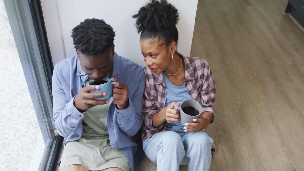 Video of happy african american couple drinking coffee and embracing at home