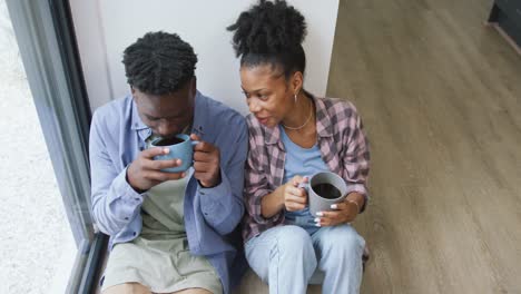 Video-of-happy-african-american-couple-drinking-coffee-and-embracing-at-home