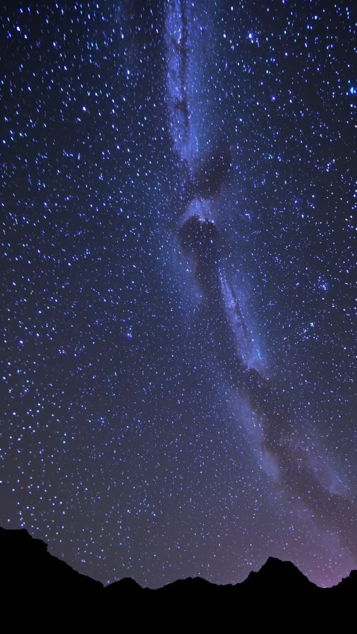 A mesmerizing night sky video captures the Milky Way with a low-angle shot, showcasing a star-filled