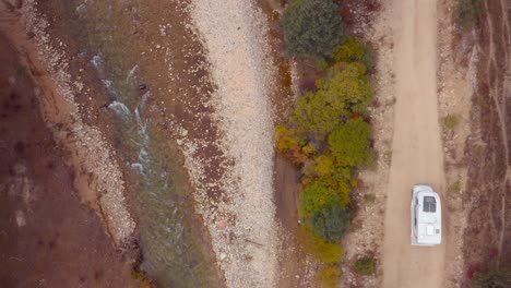 Motorhome-driving-on-a-barren-trail-along-the-banks-of-a-river