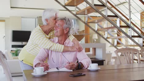 Pareja-Caucásica-Mayor-Abrazándose-Calculando-Las-Finanzas-En-Casa