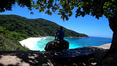 the guy is sitting on a rock and looking at lagoon