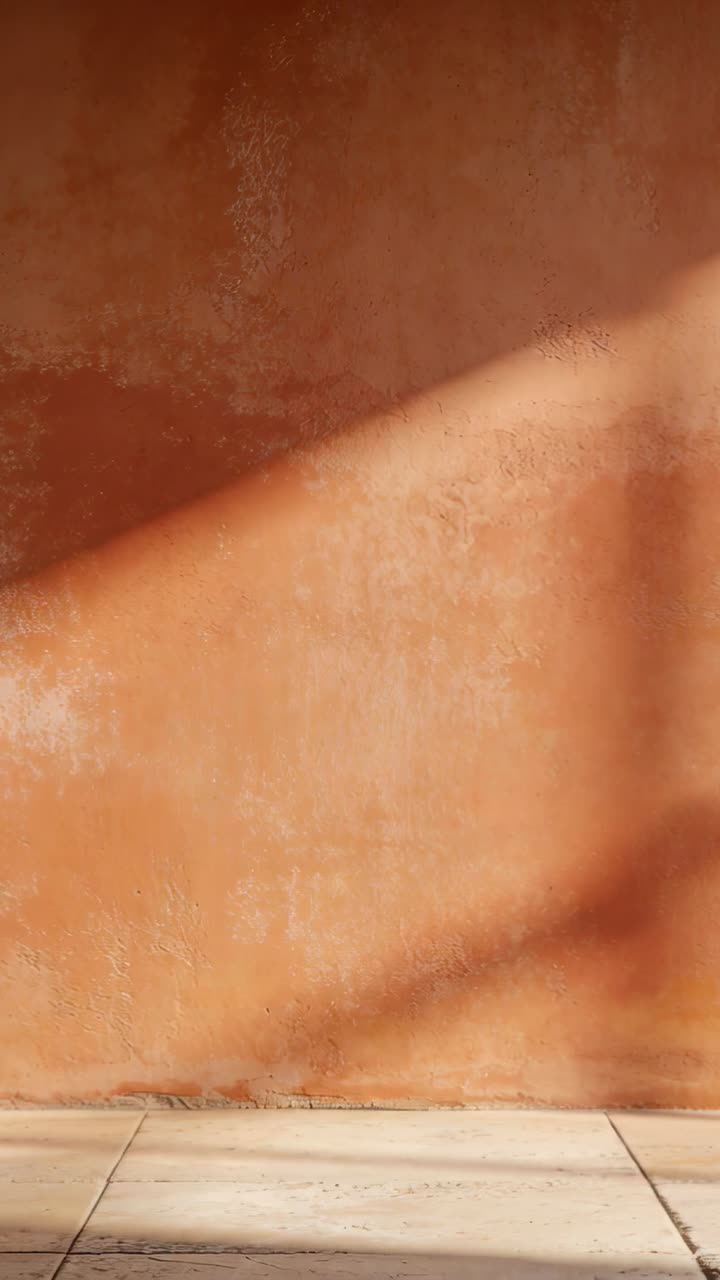 Video verticale: Sole basso che proietta dalla finestra formando una banda diagonale su una parete di intonaco arancione con piastrelle.