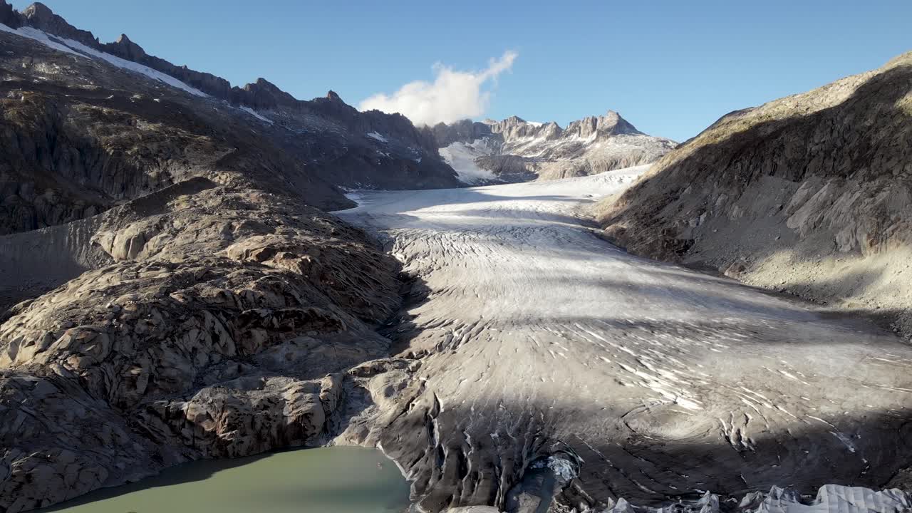 Vista aérea da geleira do Ródano perto do passo de montanha Furka na fronteira de Valais e Uri na Suíça, com uma panorâmica descendente do gelo para o lago glacial.