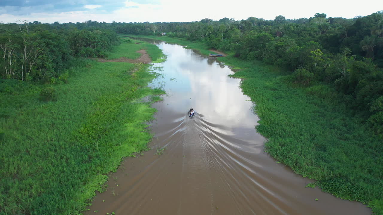toma aérea rastreando un pequeño bote que baja por el río amazonas en la selva tropical en perú